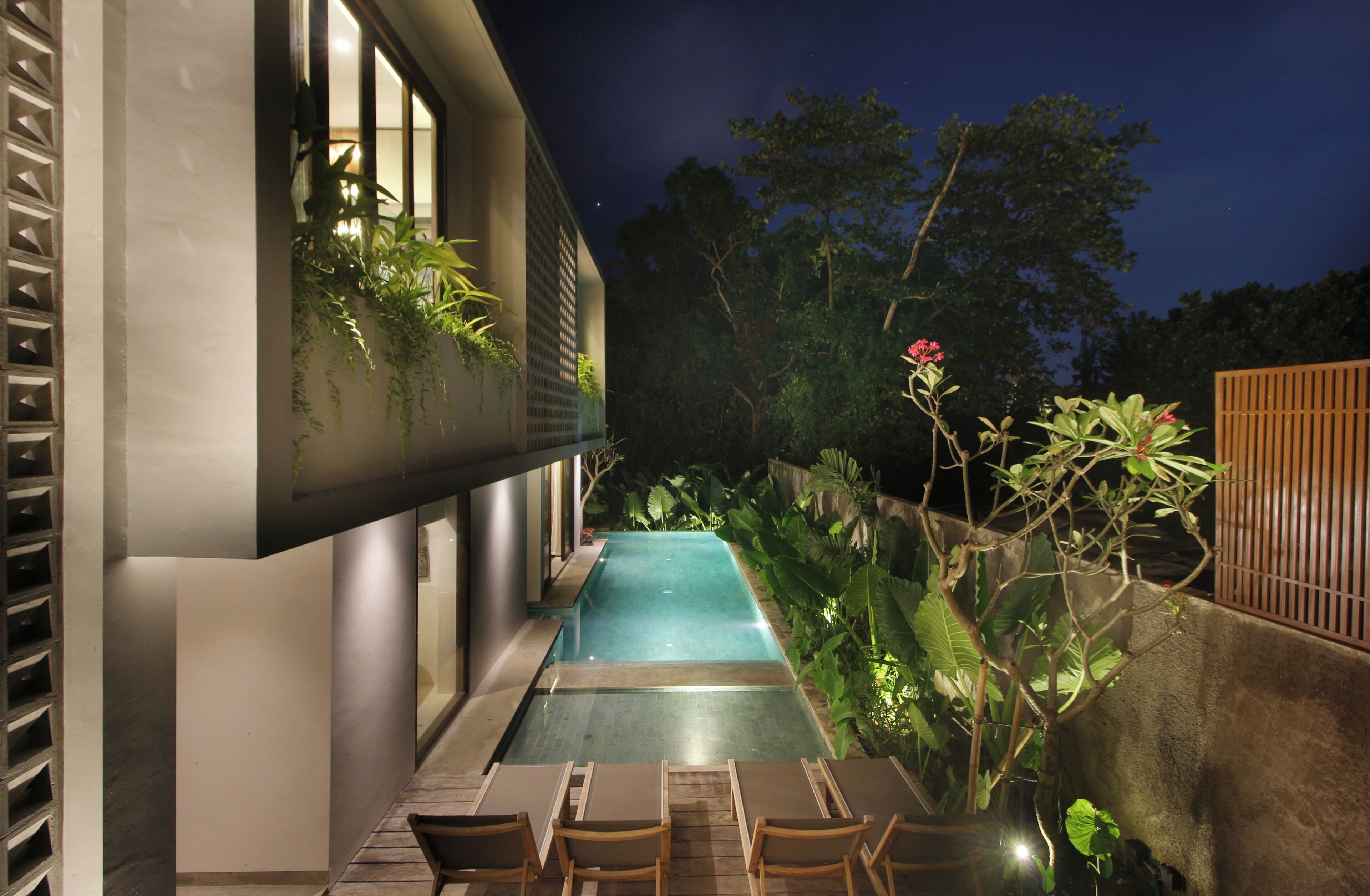 A modern outdoor pool area with a built-in bench and lush greenery.