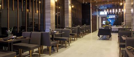 A modern restaurant with high ceilings, wooden slats, and a central bar area.