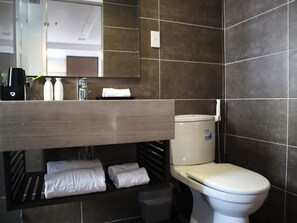Een moderne badkamer met toilet, wastafel en spiegel. Er liggen handdoeken en toiletartikelen op het aanrecht.
