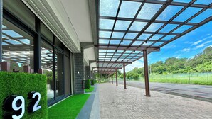 A modern building with a glass facade, a paved walkway, and a green artificial grass area. - Longtan Lake Inn (Jiaoxi)