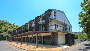 A modern multi-story building with balconies, a covered outdoor seating area, and a parking lot. - Longtan Lake Inn (Jiaoxi)