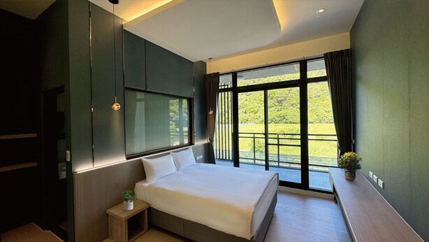 A modern bedroom with a large bed, built-in wardrobe, and a balcony with a view of greenery. - Longtan Lake Inn (Jiaoxi)