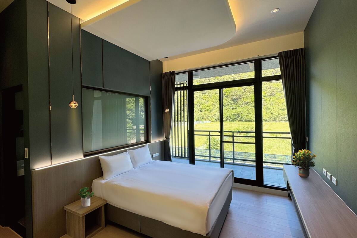 Ein modernes Schlafzimmer mit einem großen Bett, einem Einbauschrank und einem Balkon mit Blick auf Grünflächen.