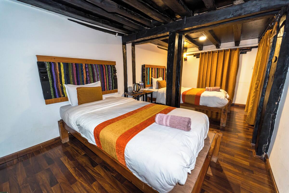 A room with a large bed, a wooden headboard, and a small table with a lamp.