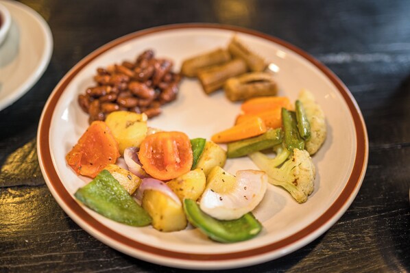 Une assiette de légumes variés, notamment des pommes de terre, des carottes, des haricots verts et des tomates.