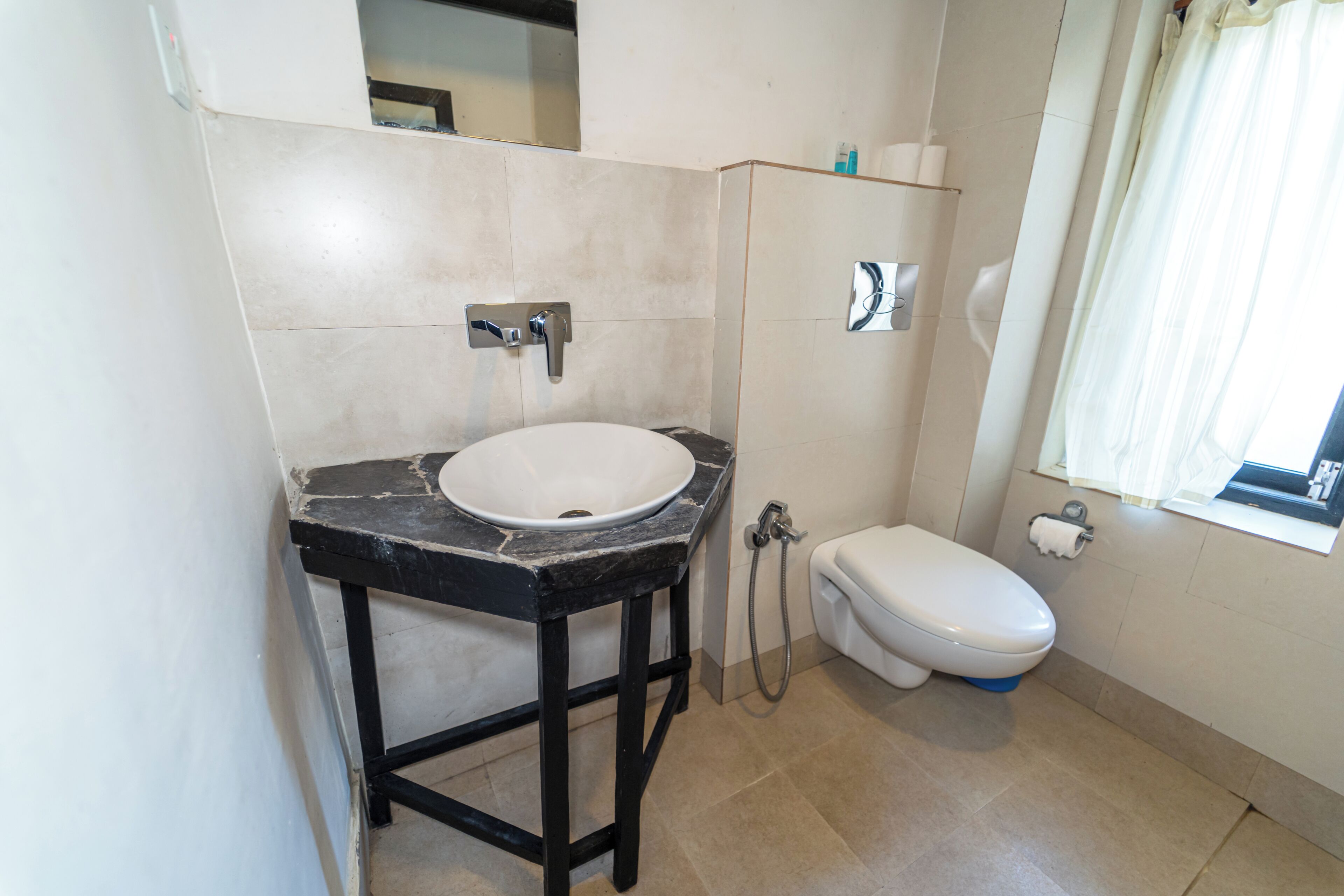 A bathroom with a white sink, black countertop, and a white toilet.