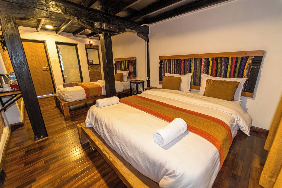 A hotel room with two beds, wooden flooring, and a large window.