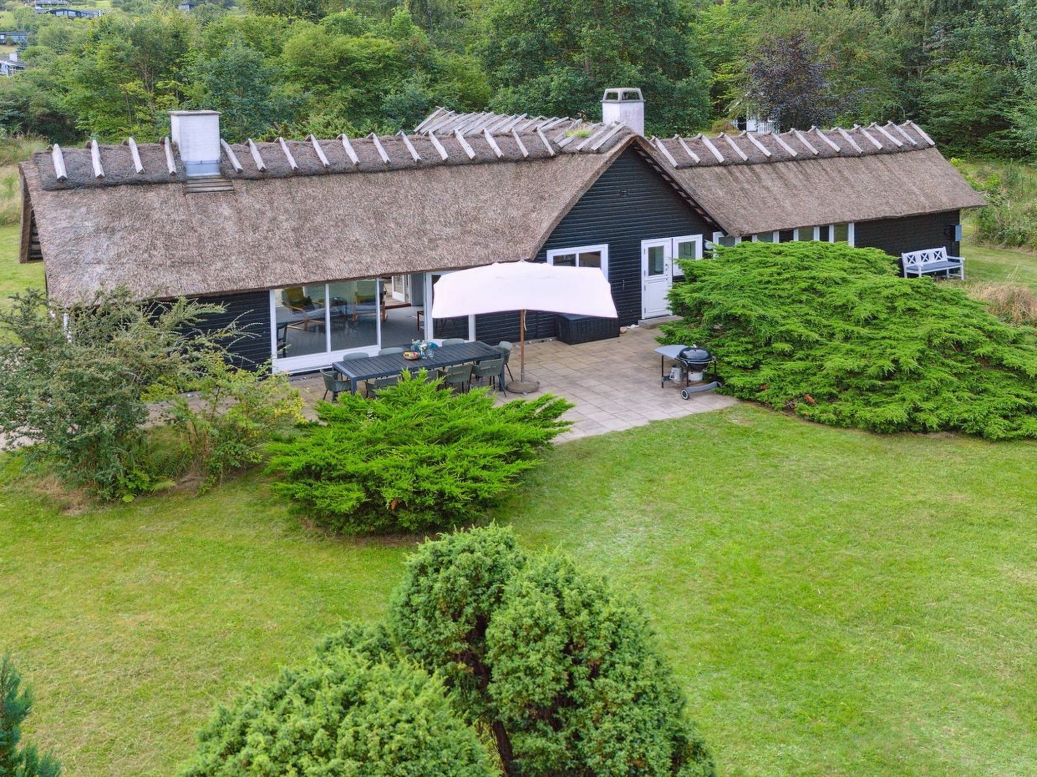 Una casa con techo de paja y un patio con zona de estar al aire libre.