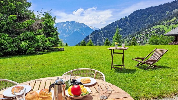 A table set outdoors with plates of food, a coffee pot, and a view of mountains. - Baudrier A05 by Interhome (Verbier)