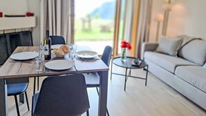 A dining area with a table set for two, a bottle of wine, and a vase with red flowers. - Baudrier A05 by Interhome (Verbier)