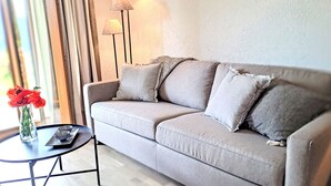 A living room with a grey sofa, a small round table with a vase of red flowers, and two floor lamps. - Baudrier A05 by Interhome (Verbier)