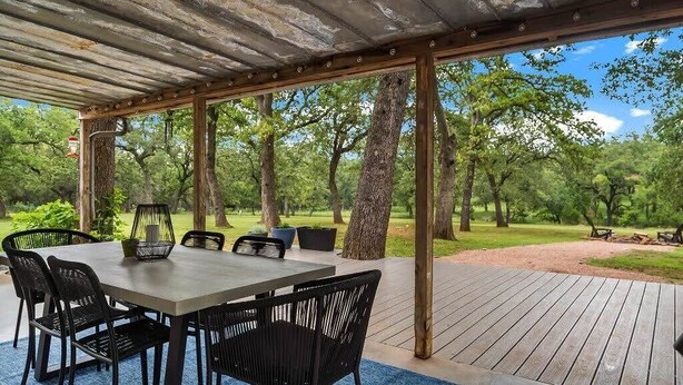 Eine Terrassengruppe mit Holztisch und -stühlen, umgeben von Bäumen.
