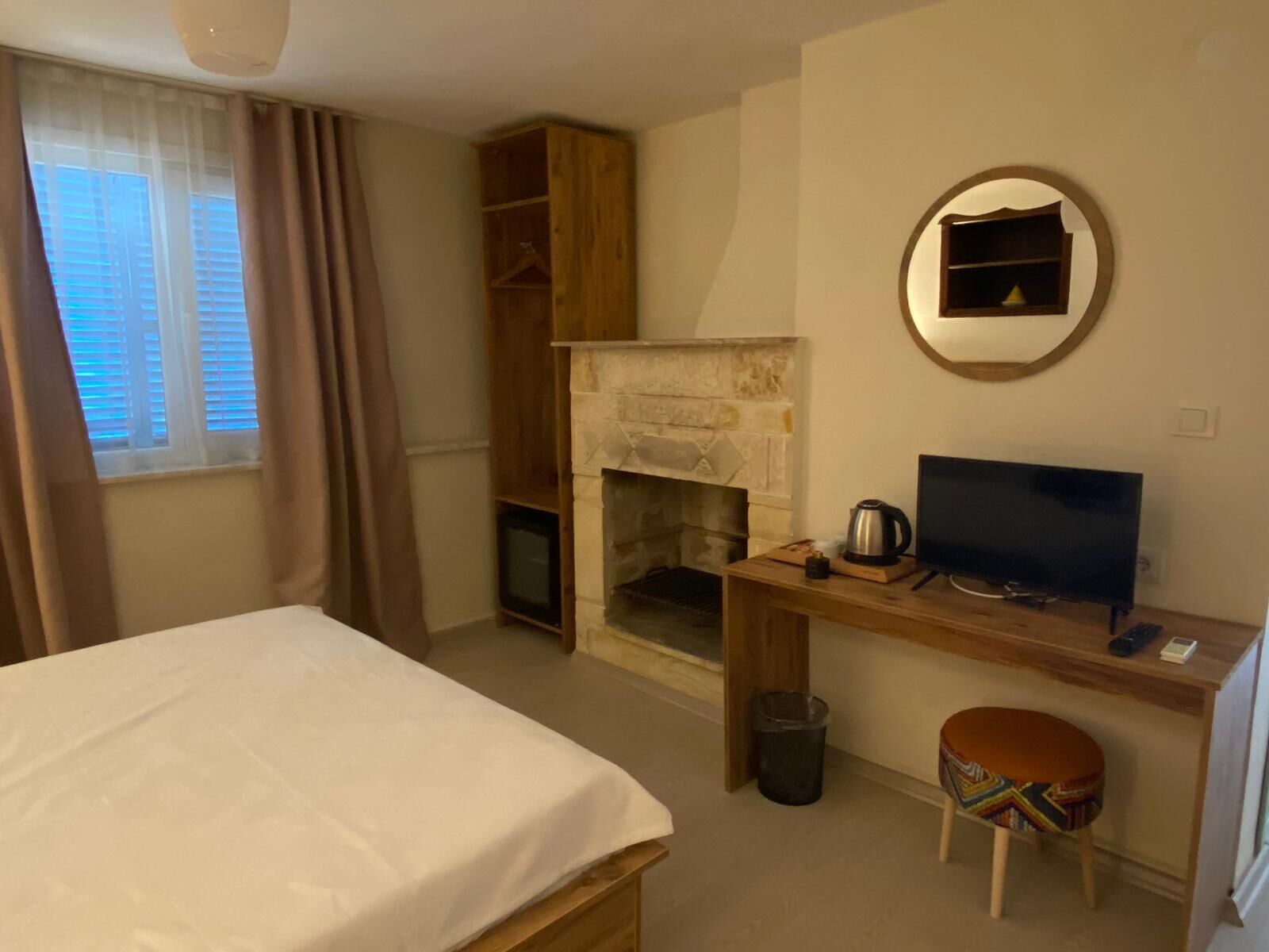 A hotel room with a bed, a desk with a computer, a fireplace, and a television.