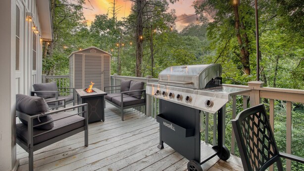 Una terraza con mobiliario exterior, una parrilla y un cobertizo pequeño.