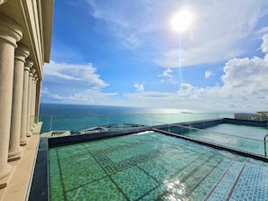 A rooftop infinity pool with clear blue water, overlooking the ocean.