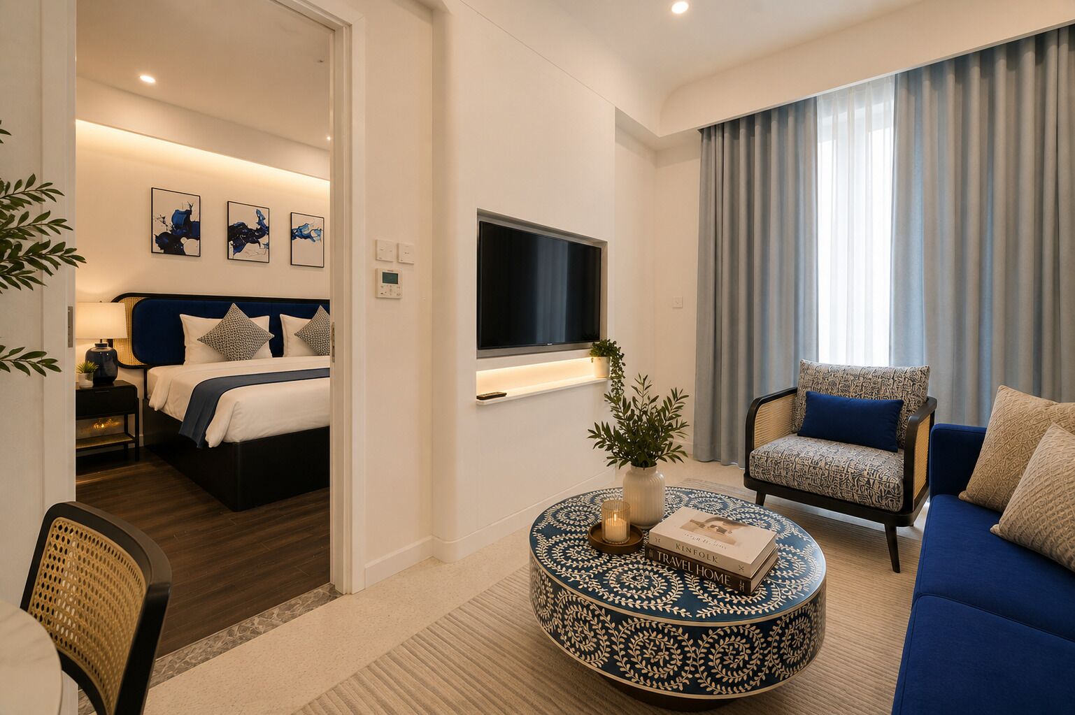 A modern hotel room with a bed, a sofa, a TV, and a coffee table.