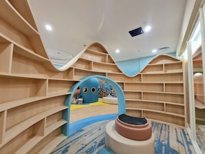 A children's play area with a slide, climbing wall, and colorful wall decorations. - Lotus Home Cafe - Apartment (Phu Quoc)