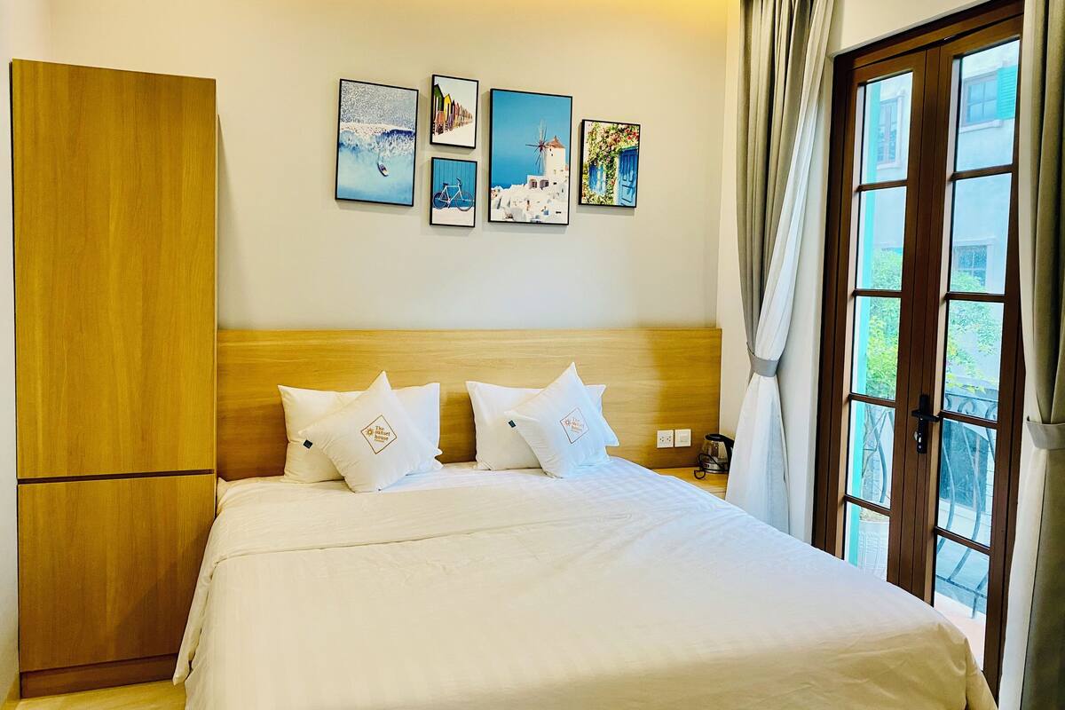 A hotel room with a bed, wooden wardrobe, and a window with curtains.