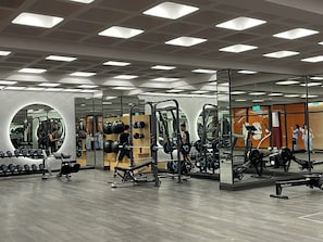 A modern gym with various exercise equipment, including weight machines and free weights. - Lotus Home Cafe - Apartment (Phu Quoc)