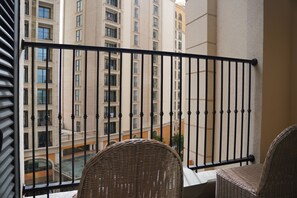 A balcony with a wrought iron railing, wicker chairs, and a view of a multi-story building with balconies. - Lotus Home Cafe - Apartment (Phu Quoc)