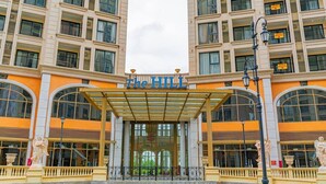 Ein Hotel mit überdachter Eingangspforte, großen Bogenfenstern und einem zentralen Eingang.