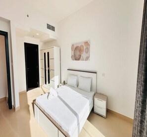 A modern bedroom with a large bed, bedside tables, a wardrobe, and a decorative wall piece. - OYO 1186 Home Orion BLDG Arjan 1 BHK (Dubai)