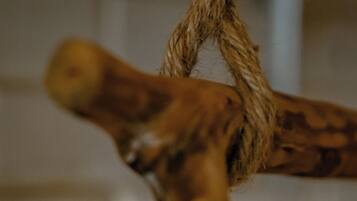A close-up of a rope tied around a wooden object, possibly a part of a piece of furniture or decor.