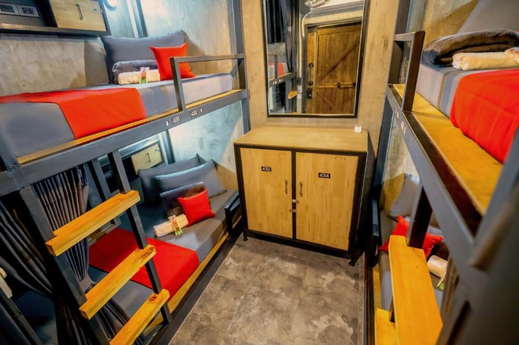 Habitación con literas compactas y de varios niveles, un pequeño armario de madera y un espejo.