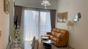 Ein modernes Wohnzimmer mit einem Ledersofa, einem Esstisch für vier Personen und einer Kronleuchter.