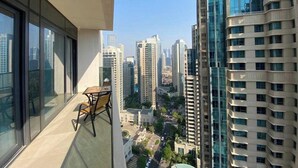 Ein Balkon mit Tisch und Stühlen, mit Blick auf eine Skyline mit Hochhäusern.