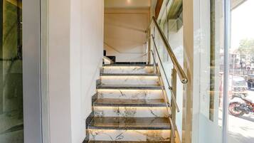 A marble staircase with a glass door leading to a street view.