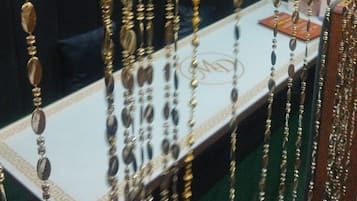 Una fila de adornos colgantes, posiblemente joyería, en una habitación con un papel tapiz estampado y un sofá oscuro.