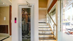 L’entrée moderne de l’hôtel se caractérise par une porte en verre, un escalier aux marches en marbre et une rampe en métal.