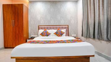A bedroom with a large bed, a wooden wardrobe, and a grey textured wall.