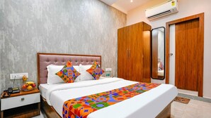 Une chambre d’hôtel moderne dotée d’un grand lit, d’une armoire en bois, d’une table de chevet avec un téléphone et un panier de fruits, ainsi que d’un appareil de climatisation.