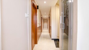 Un couloir avec des portes en bois et une porte en verre, qui mène à une pièce.
