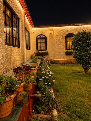 A courtyard with a building, potted plants, and a lawn. - La Address Retreat (Ootacamund)