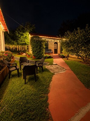 Un patio con mobiliario exterior, un sendero y un edificio con puerta y ventanas.