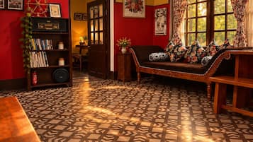 A room with a patterned floor, a wooden bench, a bookshelf, and a door leading to another room.