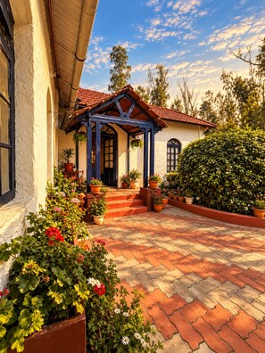A house with a red-tiled roof, a covered porch, and a brick pathway leading to the entrance. - La Address Retreat (Ootacamund)
