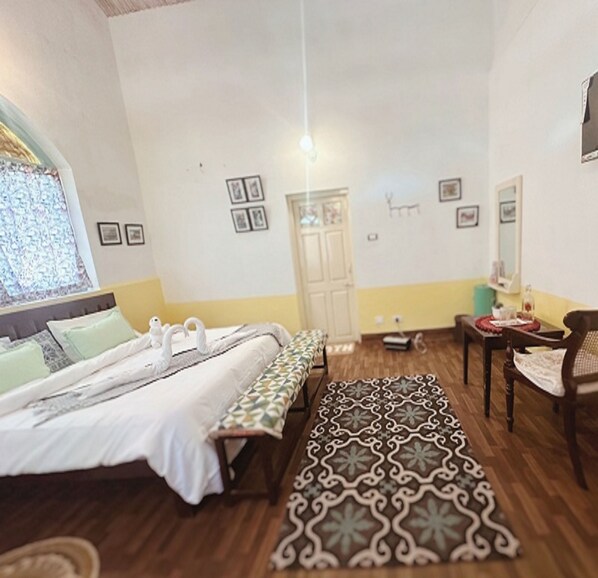 A hotel room with two beds, a sitting area with a patterned rug, a window with a view, and a door. - La Address Retreat (Ootacamund)