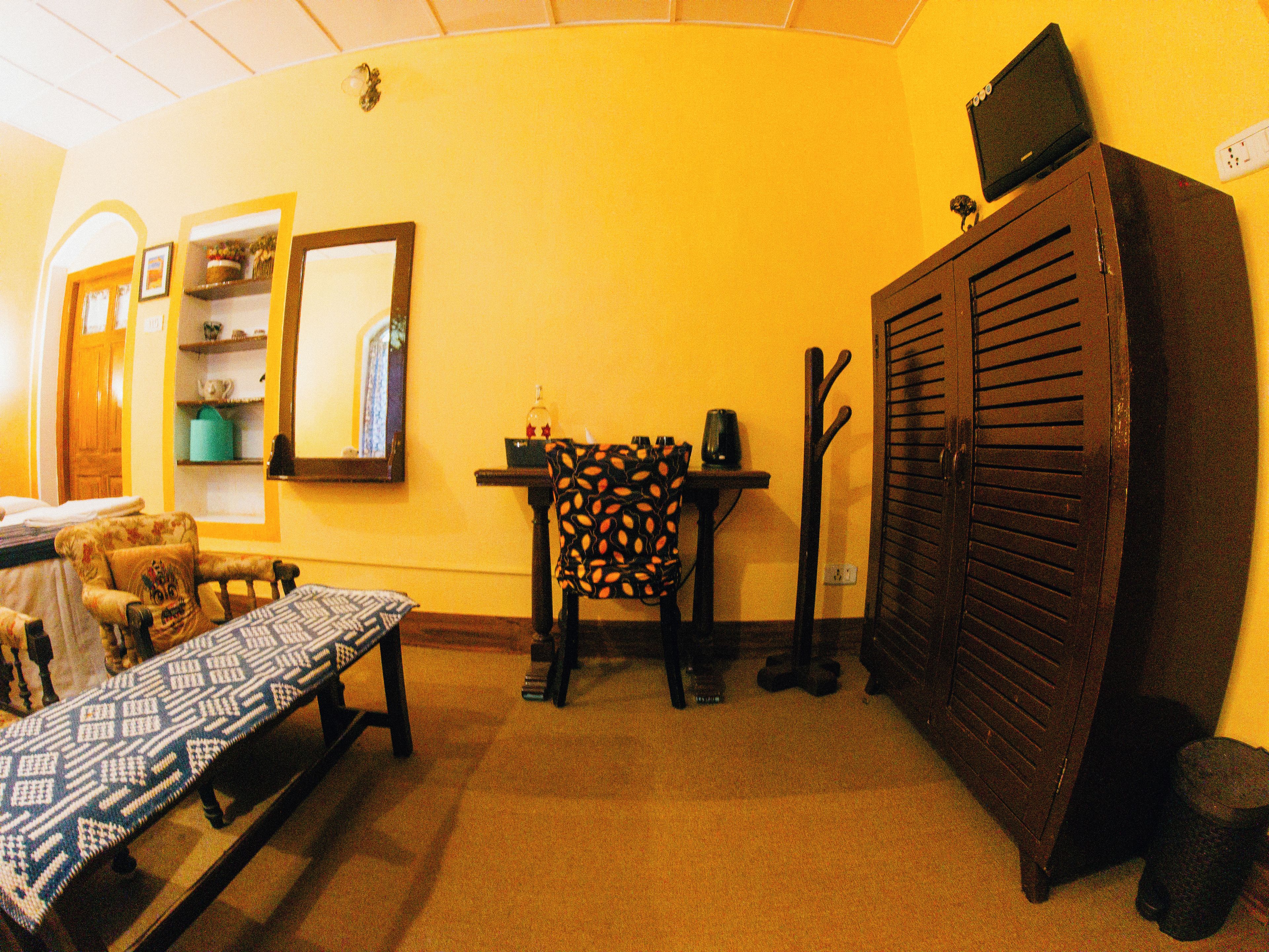 Una habitación con cama, una mesa, una silla, un armario y un espejo.