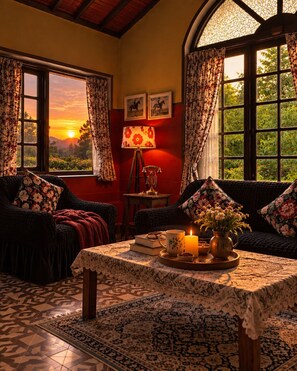 A cozy room with a sofa, a table with a candle, and a view of the sunset through the window. - La Address Retreat (Ootacamund)