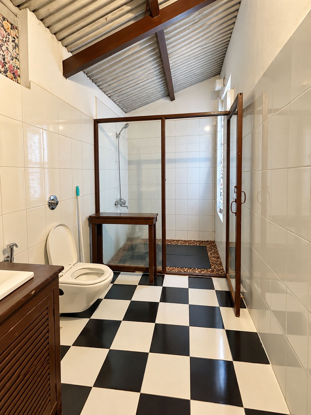 A bathroom with a checkered floor, a toilet, a sink, and a shower area.