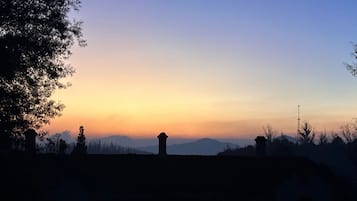 A sunset over a residential area with houses and a distant mountain range.