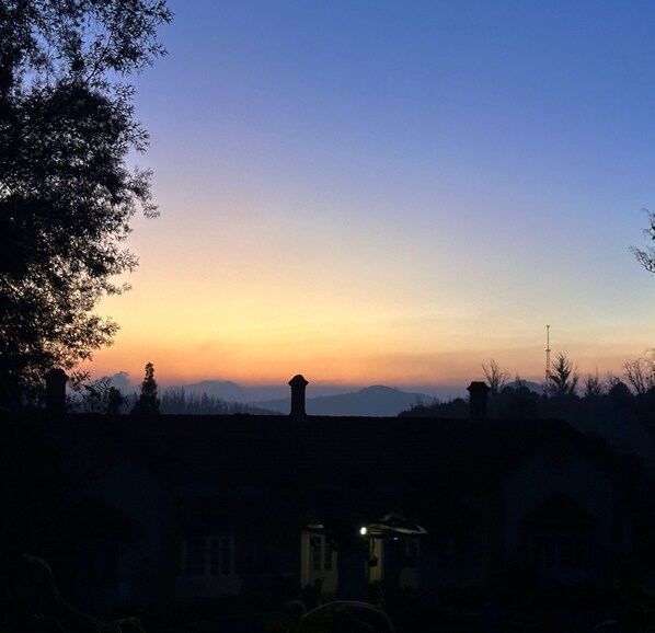 A sunset over a residential area with houses and a distant mountain range. - La Address Retreat (Ootacamund)
