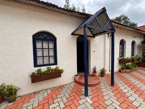 A building with a white exterior, blue window frames, and a tiled patio area. - La Address Retreat (Ootacamund)