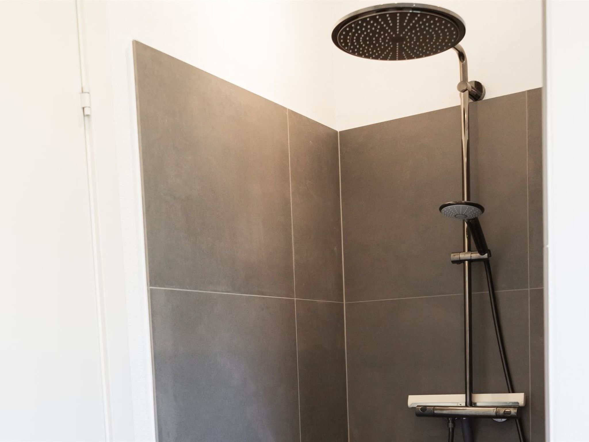 Eine moderne Dusche mit Handbrause und einer fest installierten Regendusche.