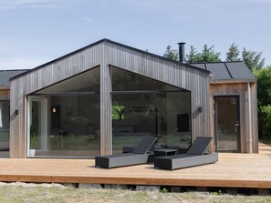 Una casa moderna con un porche acristalado y mobiliario para disfrutar del exterior.