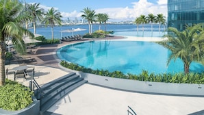 A modern pool area with lounge chairs, palm trees, and a view of the city skyline. - NUSTAR Hotel Cebu (Cebu City)
